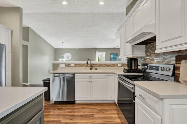 kitchen featuring tasteful backsplash, light countertops, appliances with stainless steel finishes, and under cabinet range hood