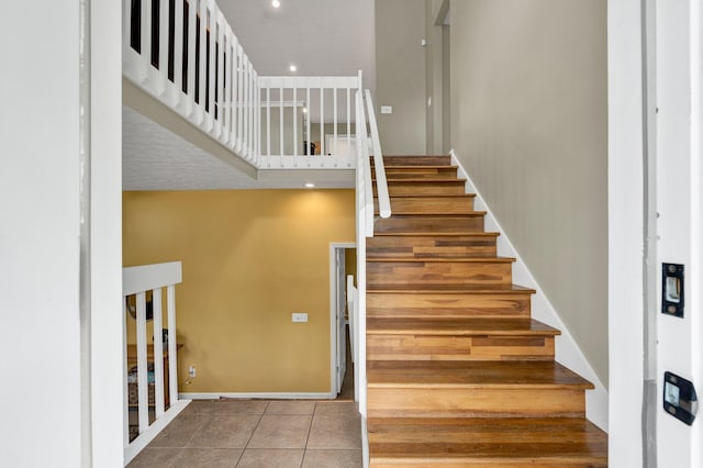 stairs featuring baseboards, tile patterned flooring, and a towering ceiling