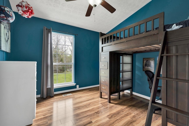 bedroom with a textured ceiling, vaulted ceiling, visible vents, wood finished floors, and baseboards