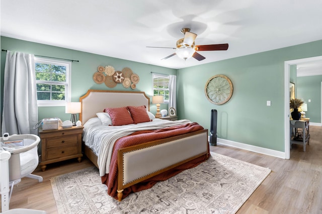 bedroom featuring light wood finished floors, baseboards, and a ceiling fan