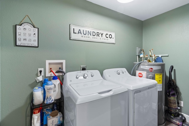 clothes washing area featuring laundry area, water heater, and washer and clothes dryer