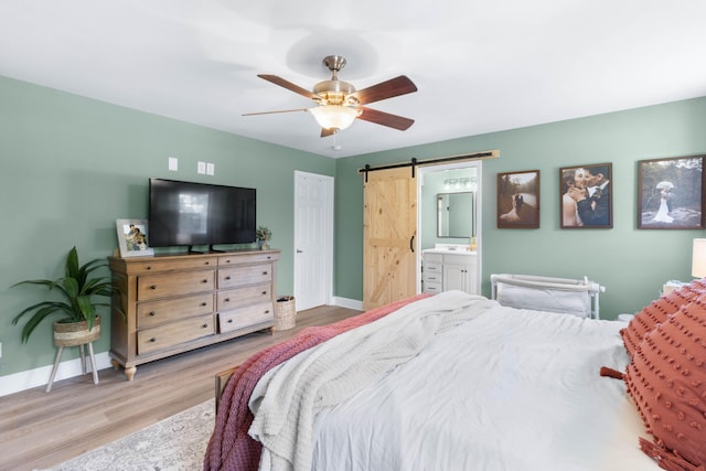 bedroom with a barn door, baseboards, ceiling fan, and wood finished floors