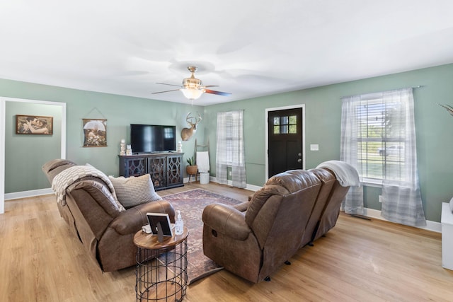 living room with baseboards, ceiling fan, and light wood-style floors