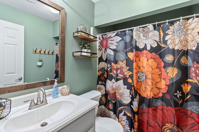 full bathroom featuring toilet, a textured wall, a shower with shower curtain, and vanity