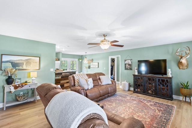 living room with a ceiling fan, baseboards, and wood finished floors