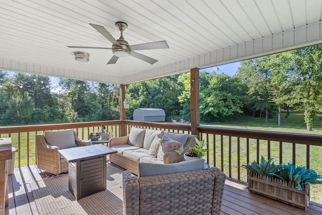 deck with an outbuilding, outdoor lounge area, a ceiling fan, a yard, and a storage unit