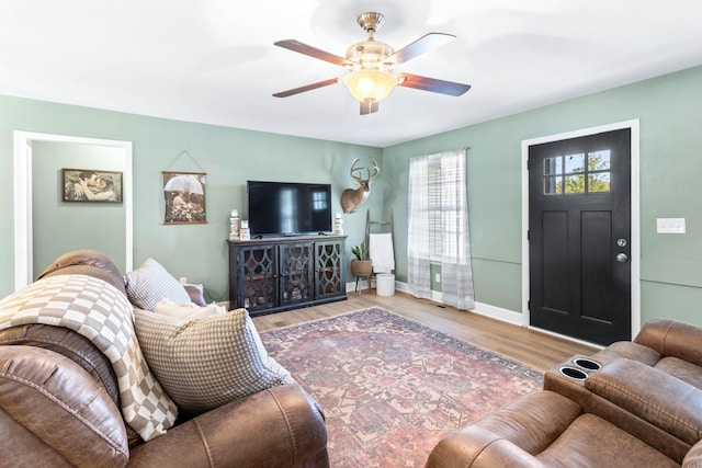 living room with ceiling fan, baseboards, and wood finished floors