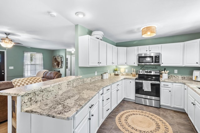 kitchen with stainless steel appliances, white cabinets, a peninsula, and light stone countertops