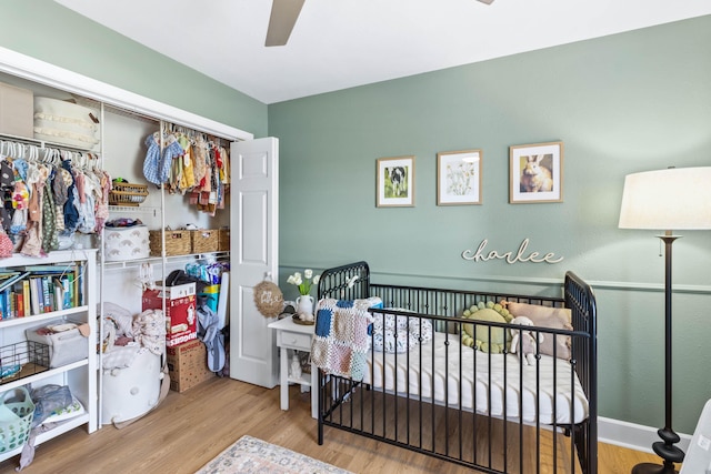 bedroom with a closet, wood finished floors, a ceiling fan, and baseboards