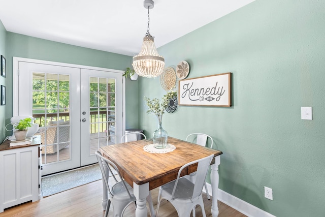 dining area featuring a notable chandelier, french doors, wood finished floors, and baseboards