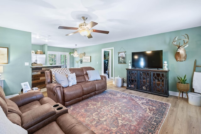 living room with a ceiling fan, baseboards, and wood finished floors