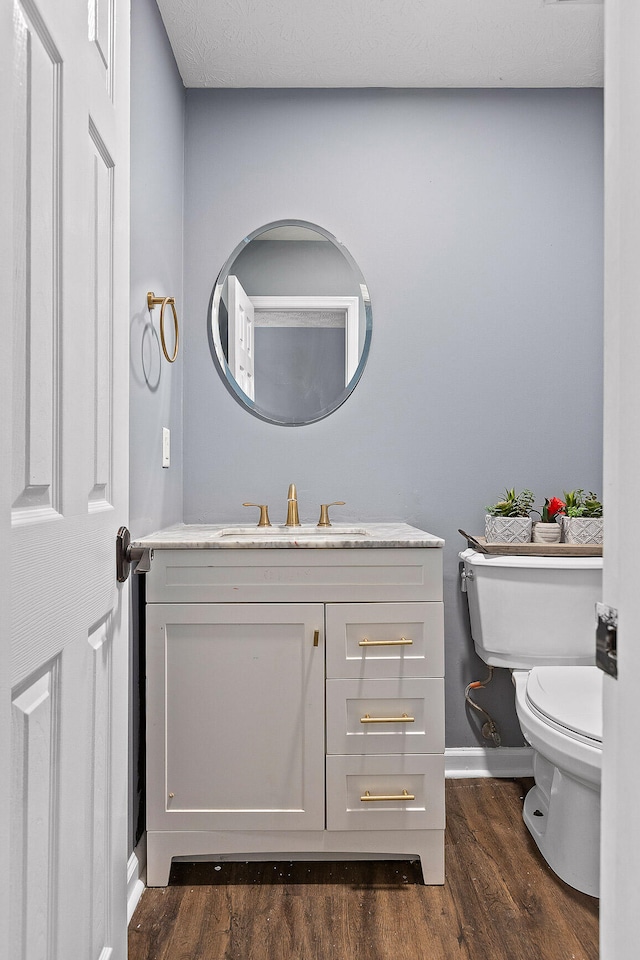 bathroom with hardwood / wood-style floors, vanity, and toilet