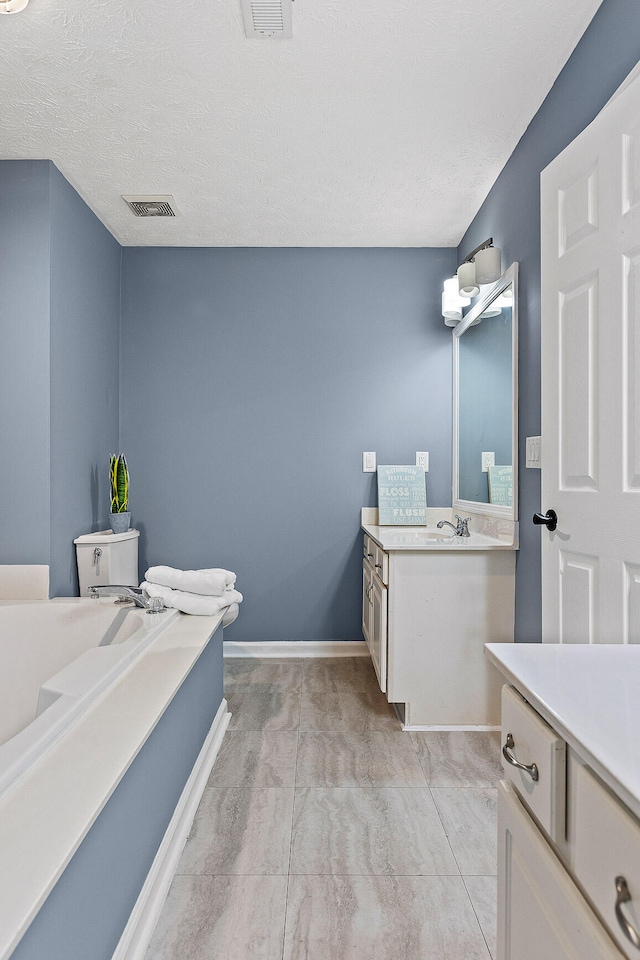 bathroom featuring tile patterned flooring, vanity, a textured ceiling, and toilet