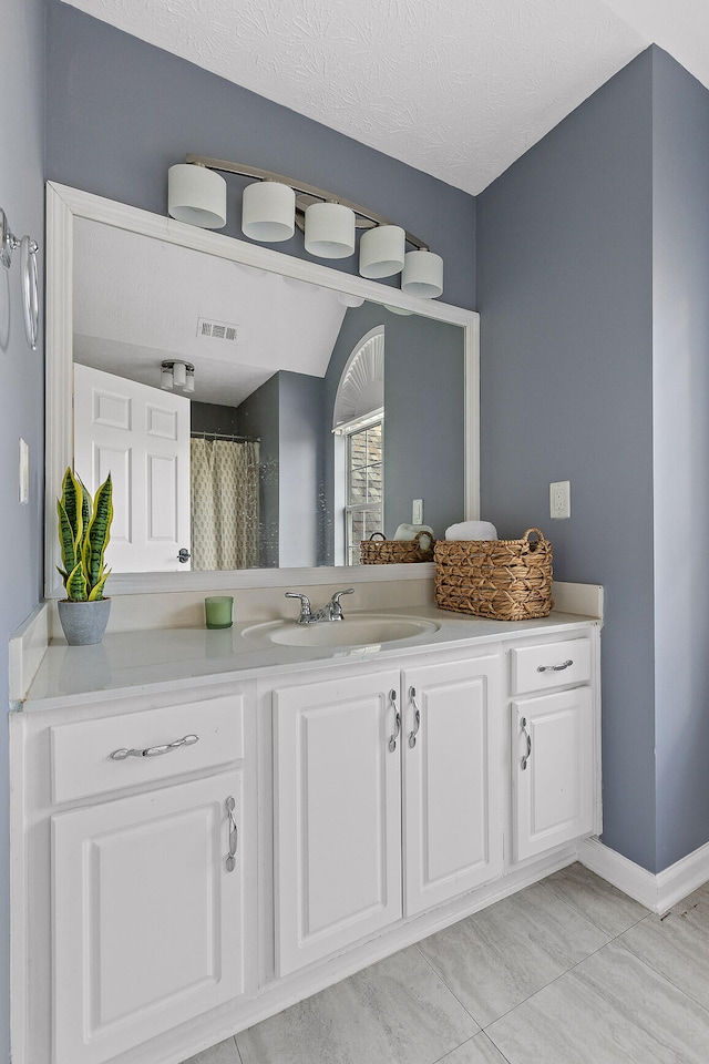 bathroom with vaulted ceiling, vanity, and a textured ceiling