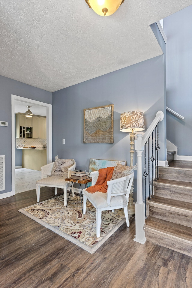 living area featuring a textured ceiling, ceiling fan, and dark wood-type flooring