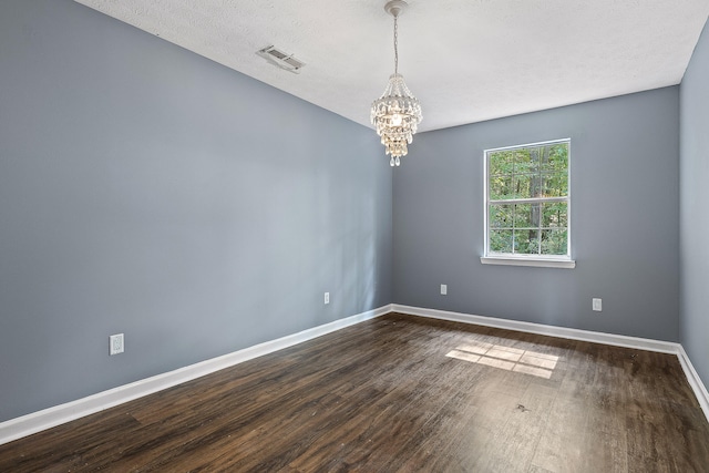 unfurnished room featuring dark hardwood / wood-style flooring, a textured ceiling, and an inviting chandelier