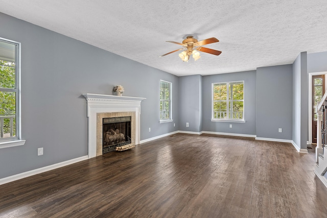 unfurnished living room featuring a textured ceiling, ceiling fan, dark hardwood / wood-style flooring, and plenty of natural light