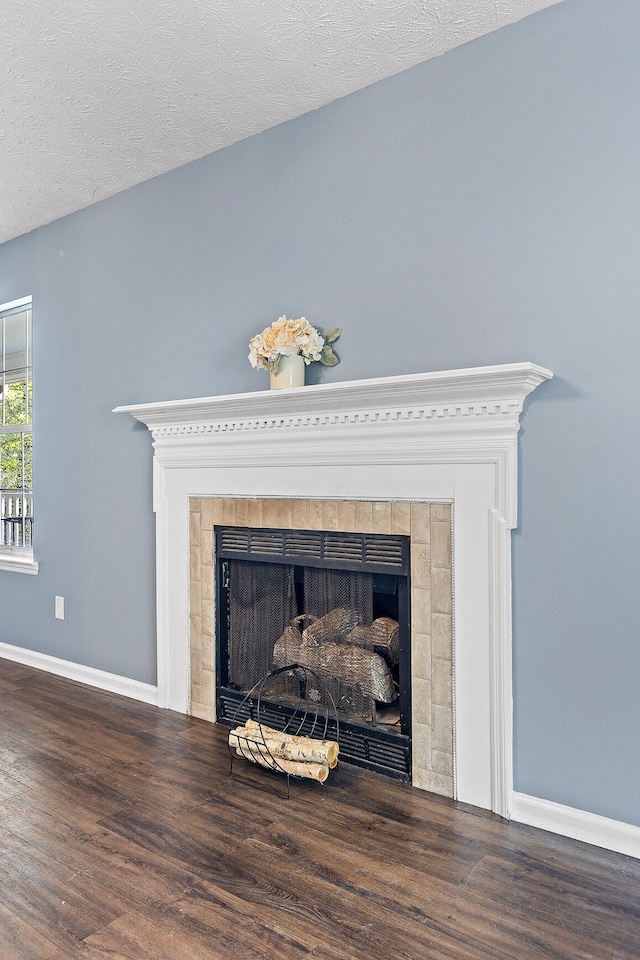 details with hardwood / wood-style flooring, a textured ceiling, and a tiled fireplace