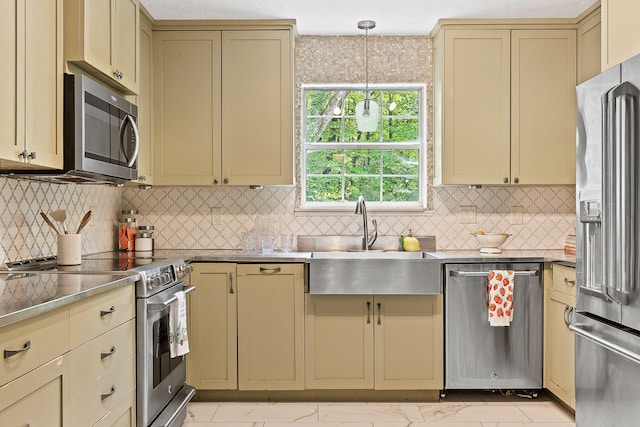 kitchen featuring cream cabinetry, premium appliances, hanging light fixtures, and sink