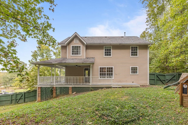 back of property featuring a lawn, ceiling fan, and a wooden deck