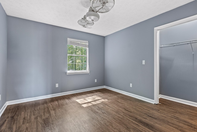 unfurnished room with a textured ceiling, ceiling fan, and dark wood-type flooring