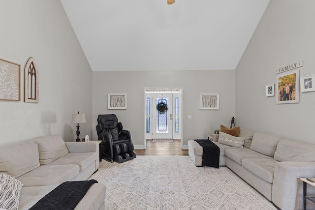 living area featuring high vaulted ceiling, wood finished floors, and baseboards
