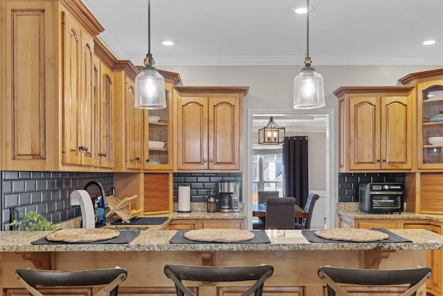 kitchen with glass insert cabinets, crown molding, hanging light fixtures, and a kitchen bar
