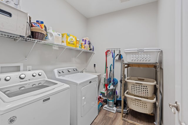clothes washing area featuring wood finished floors, laundry area, visible vents, and separate washer and dryer