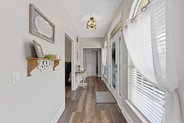 doorway featuring baseboards and dark wood-style flooring