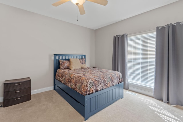 bedroom featuring light carpet, ceiling fan, multiple windows, and baseboards