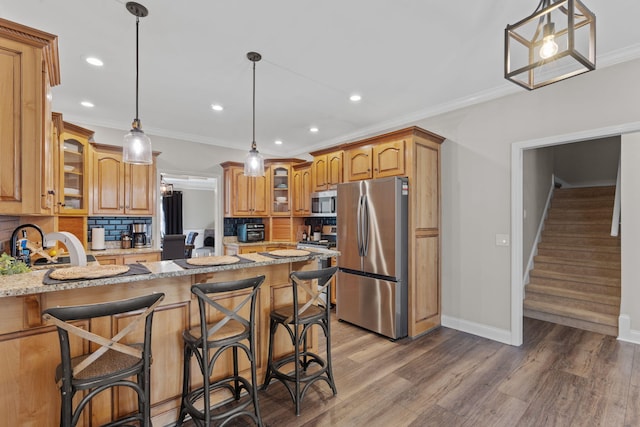 kitchen with light stone countertops, appliances with stainless steel finishes, decorative backsplash, brown cabinets, and crown molding