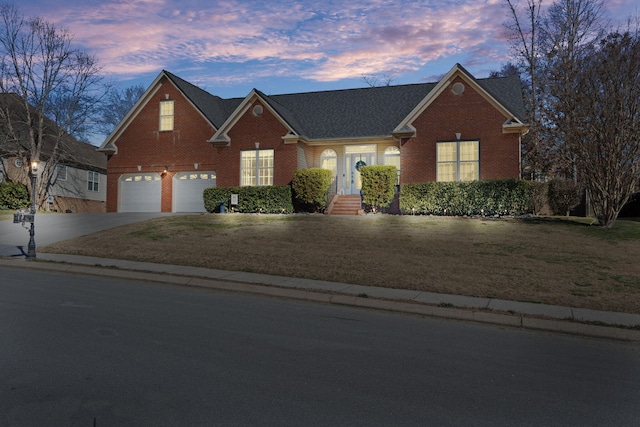 view of front of property featuring a yard, brick siding, driveway, and an attached garage