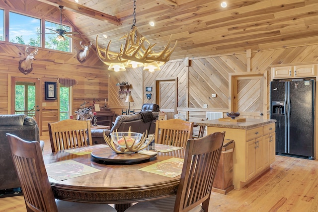 dining room with wood walls, beam ceiling, and light hardwood / wood-style floors