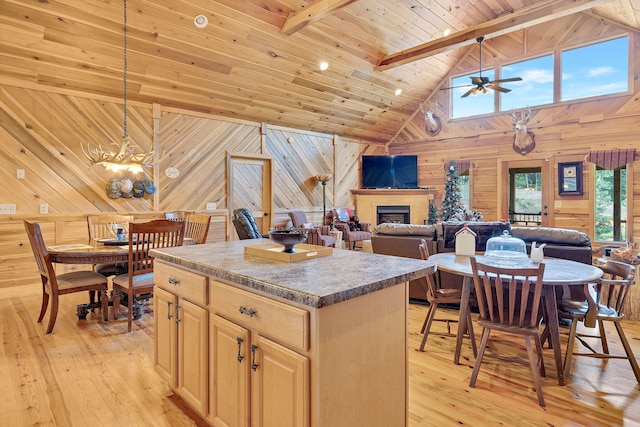 kitchen with beam ceiling, high vaulted ceiling, light hardwood / wood-style floors, a kitchen island, and wood walls