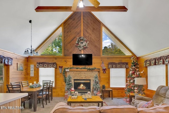 carpeted living room featuring a fireplace, wood walls, beam ceiling, and high vaulted ceiling