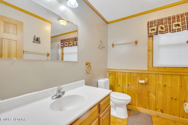 bathroom featuring hardwood / wood-style flooring, toilet, wooden walls, vanity, and ornamental molding