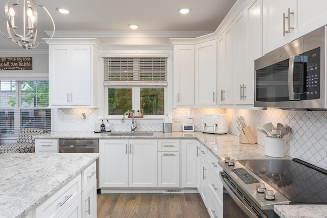 5013 Solar Ln NW, Cleveland, TN 37312 - kitchen with stainless steel appliances, a chandelier, crown molding, white cabinetry, and tasteful backsplash