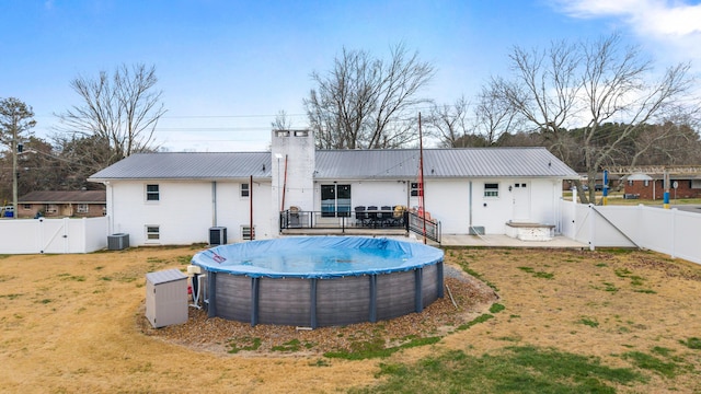 rear view of house featuring a yard, cooling unit, and a covered pool