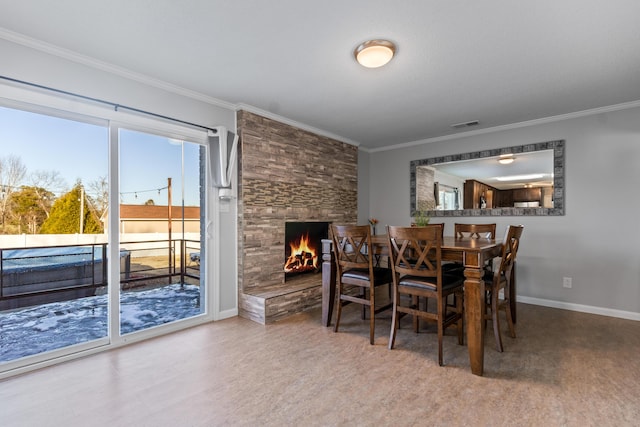 dining room with wood-type flooring, ornamental molding, and a stone fireplace