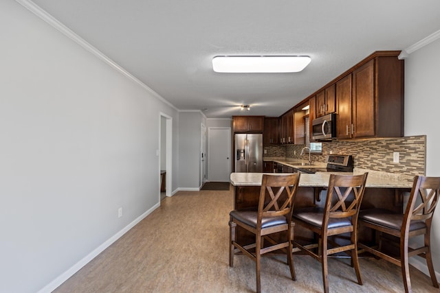 kitchen featuring appliances with stainless steel finishes, a kitchen bar, tasteful backsplash, kitchen peninsula, and crown molding