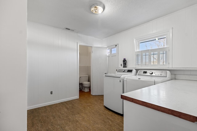 laundry room featuring washing machine and dryer, wood walls, a textured ceiling, and dark carpet