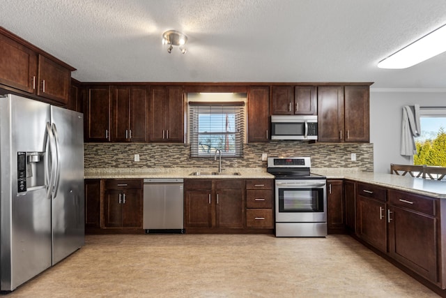 kitchen with appliances with stainless steel finishes, a healthy amount of sunlight, kitchen peninsula, and sink