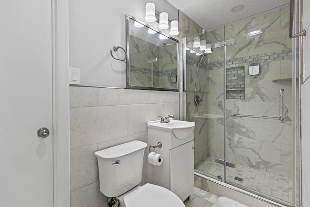 bathroom featuring vanity, toilet, tile walls, and a shower with door