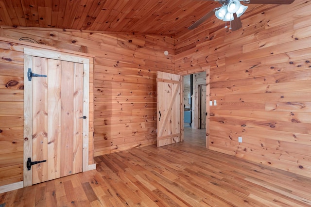 empty room with wooden ceiling, wooden walls, light hardwood / wood-style flooring, vaulted ceiling, and ceiling fan