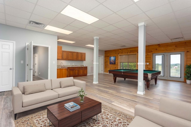 living room featuring a paneled ceiling, wood walls, sink, billiards, and light wood-type flooring