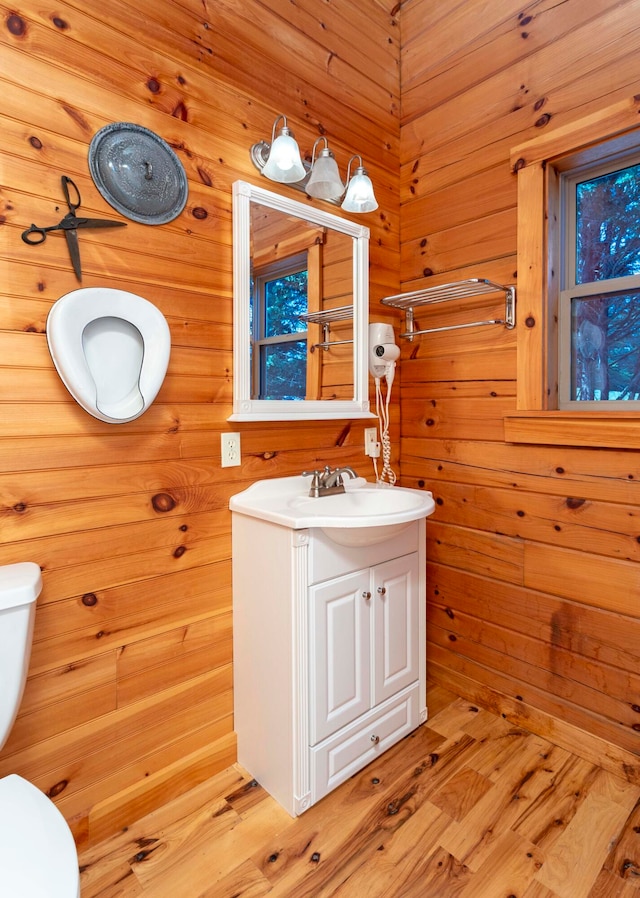 bathroom with vanity, hardwood / wood-style flooring, toilet, and wood walls