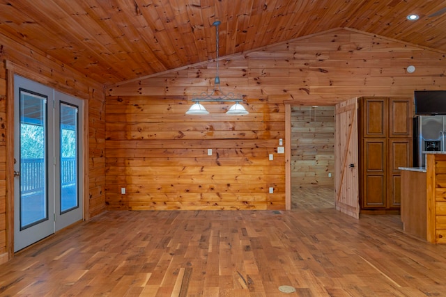 unfurnished dining area featuring lofted ceiling, light wood-type flooring, wooden walls, and wooden ceiling