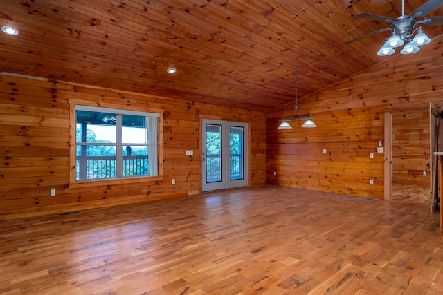 unfurnished living room featuring wood walls, wood ceiling, lofted ceiling, and light wood-type flooring