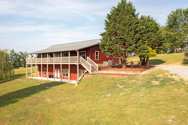 rear view of property with a lawn, a wooden deck, a patio area, and central AC