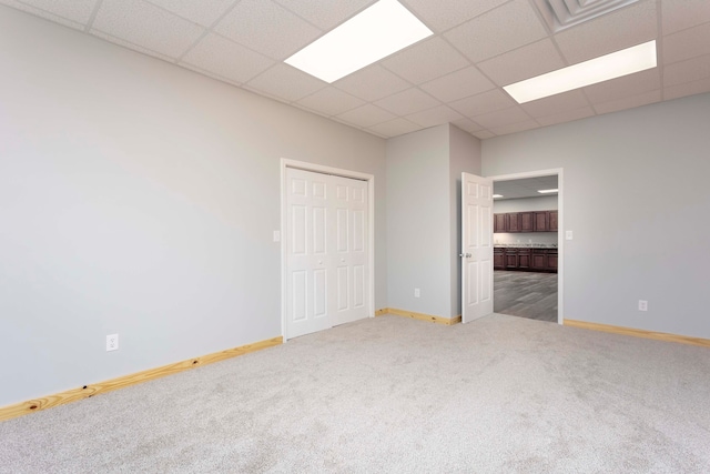 carpeted spare room featuring a drop ceiling